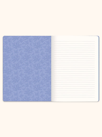 An open lined notebook with a light blue patterned cover on the left and blank white lined pages on the right, shown against a warm off-white background.