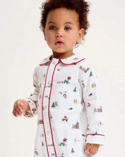 Child wearing a white pajama top with Christmas-themed print on a light background