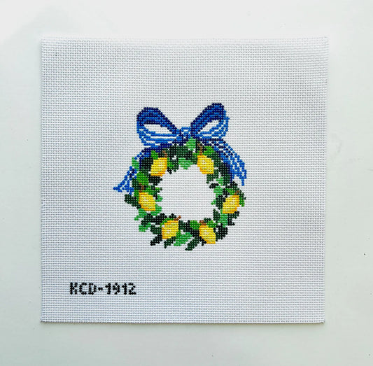Cross-stitched wreath with blue ribbon on a white background