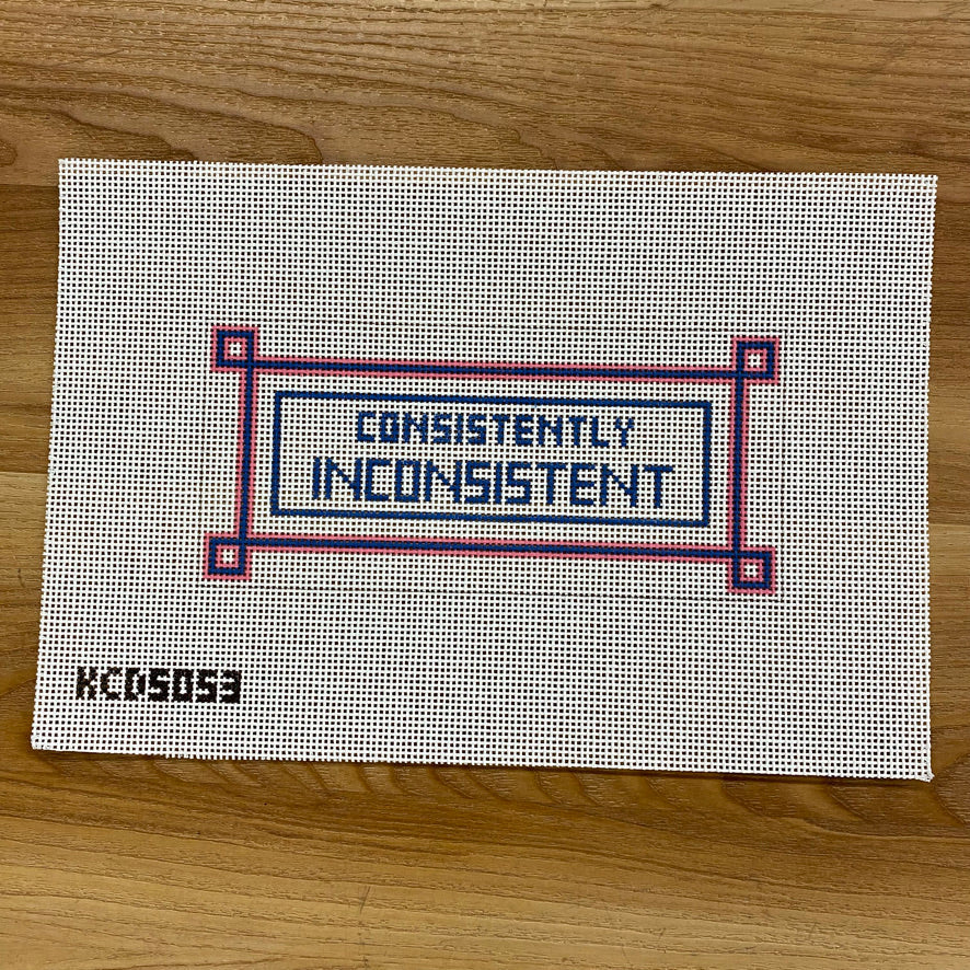 Textile panel with 'CONSISTENTLY INCONSISTENT' text on a wooden surface