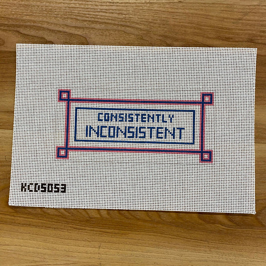 Textile panel with 'CONSISTENTLY INCONSISTENT' text on a wooden surface