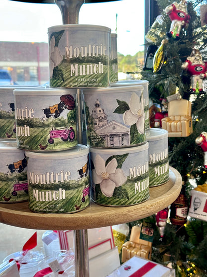 Stack of Moultrie Munch cat food cans on a wooden stand with a Christmas tree in the background.
