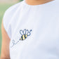 Child wearing a white shirt with a bee design on a blurred green background