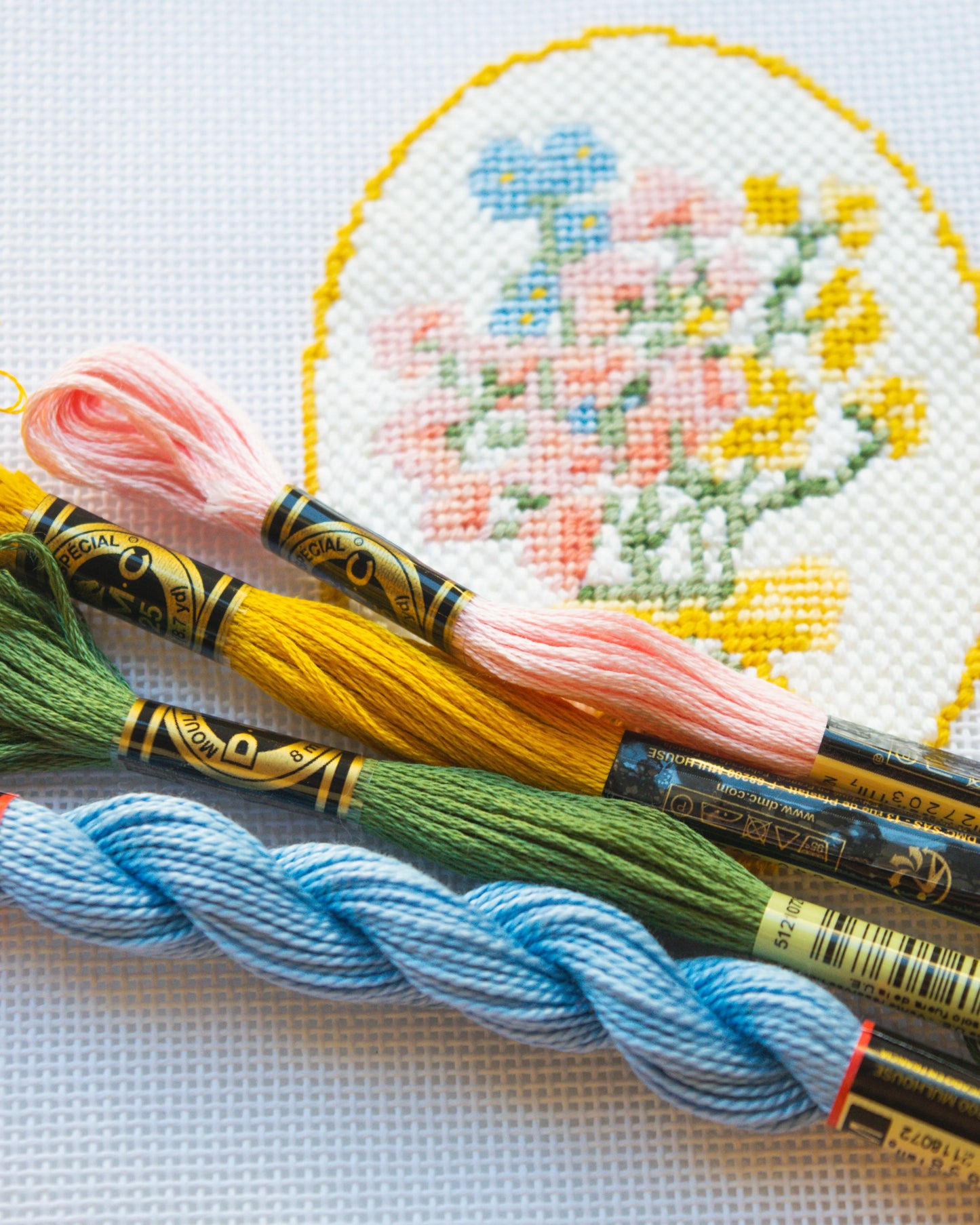 Embroidery floss with needlepoint floral design in the background