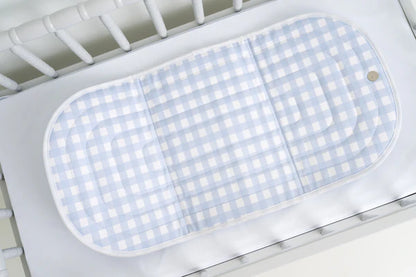 Blue and white checkered mat on a white crib