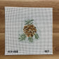 Cross-stitched pineapple design on a fabric canvas with 'SCT' branding, on a wooden surface.