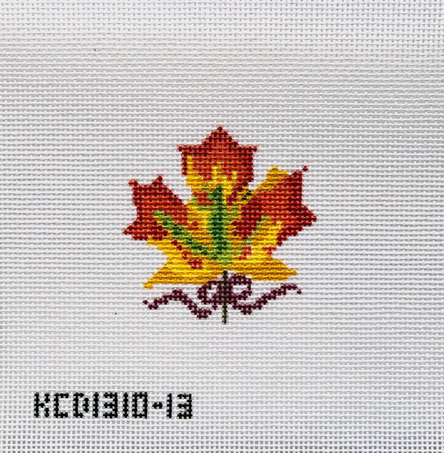 Embroidered maple leaf design on fabric with a visible brand label.