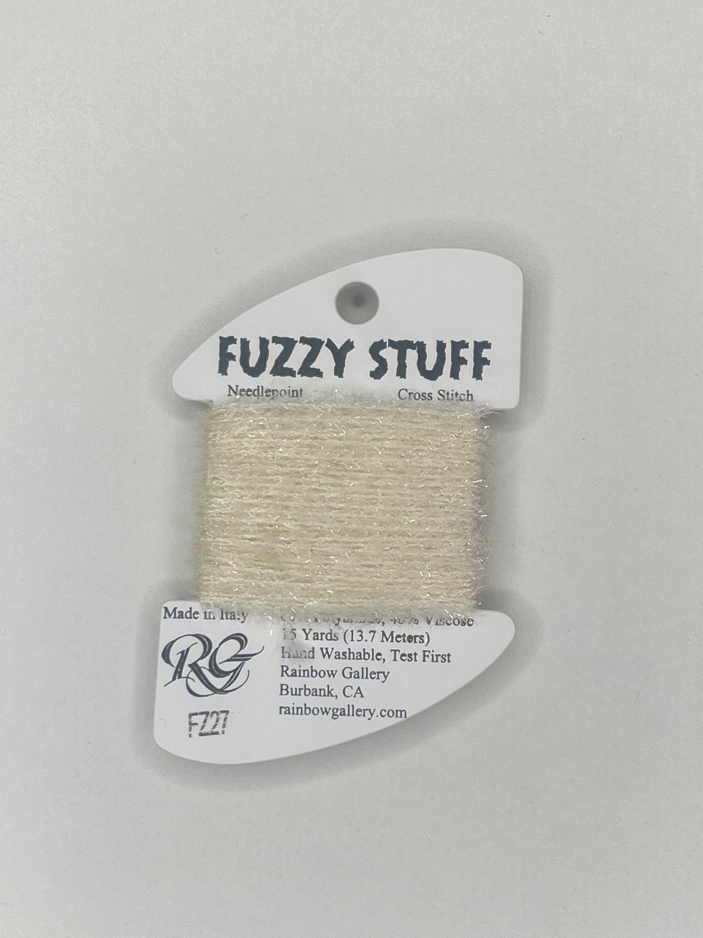 Spool of beige yarn with 'Fuzzy Stuff' label on a gray background