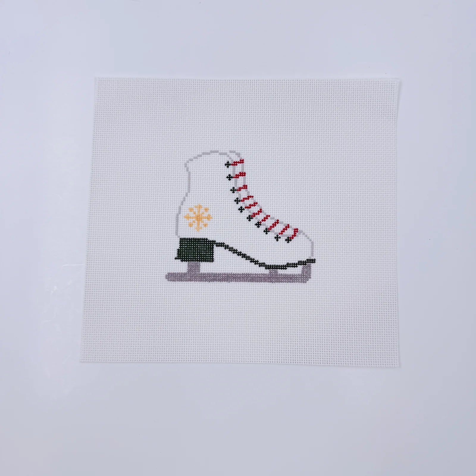 Cross-stitched ice skate on a white fabric background