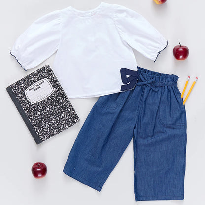 White shirt and blue pants with a notebook and apples on a light background