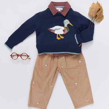 Children's navy sweater with duck design and beige pants on a white background