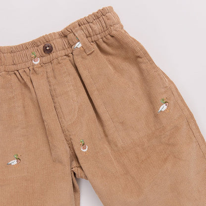 Brown corduroy pants with decorative buttons on a light gray background