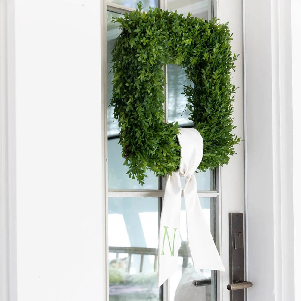 Green wreath with a white ribbon on a glass door