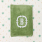 Green towel with a white monogram on a patterned background