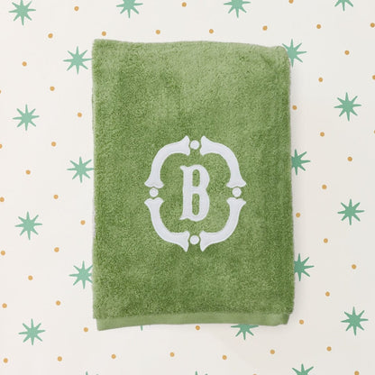 Green towel with a white monogram on a patterned background