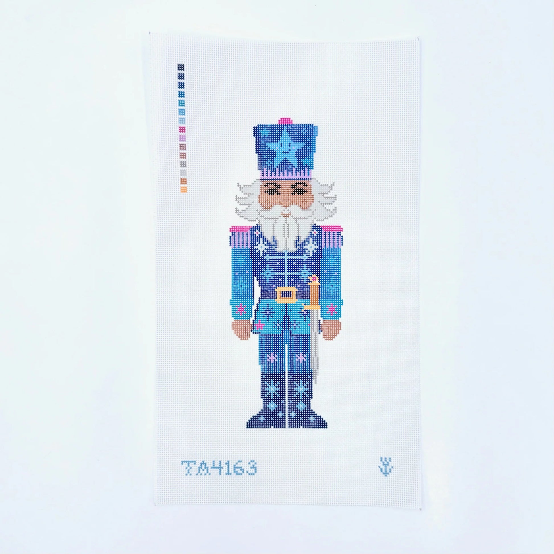 A needlepoint canvas featuring a pixelated nutcracker design in shades of blue, white, and pink, with a color palette strip on the left and the number TA4163 at the bottom.
