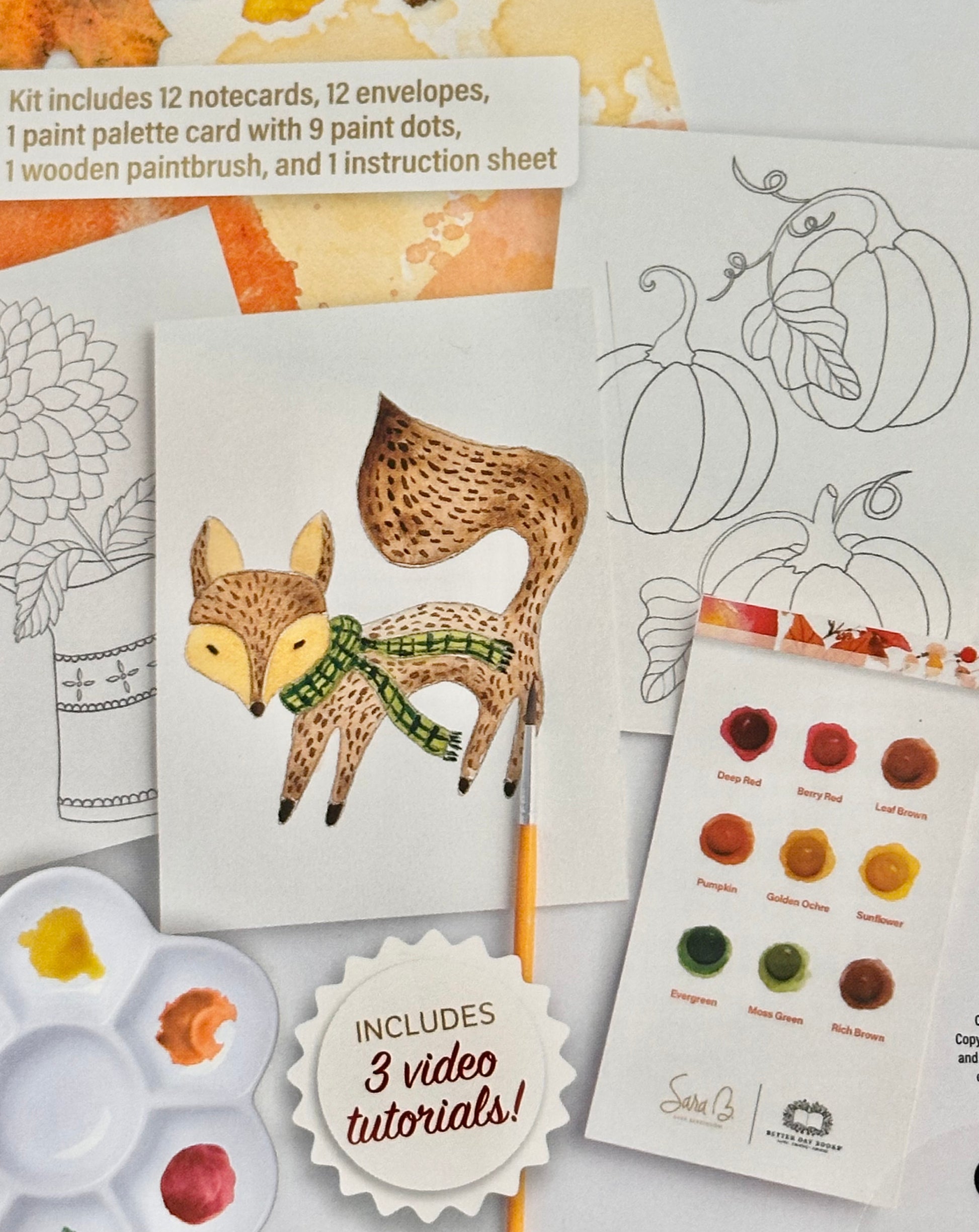 A fall-themed art kit by Sarah & Son featuring a watercolor fox illustration on a white card, surrounded by 12 notecards, 12 envelopes, a paint palette card with 9 paint dots, a wooden paintbrush, and an instruction sheet. A paint palette with paint wells and a yellow pencil are also visible on a white background.