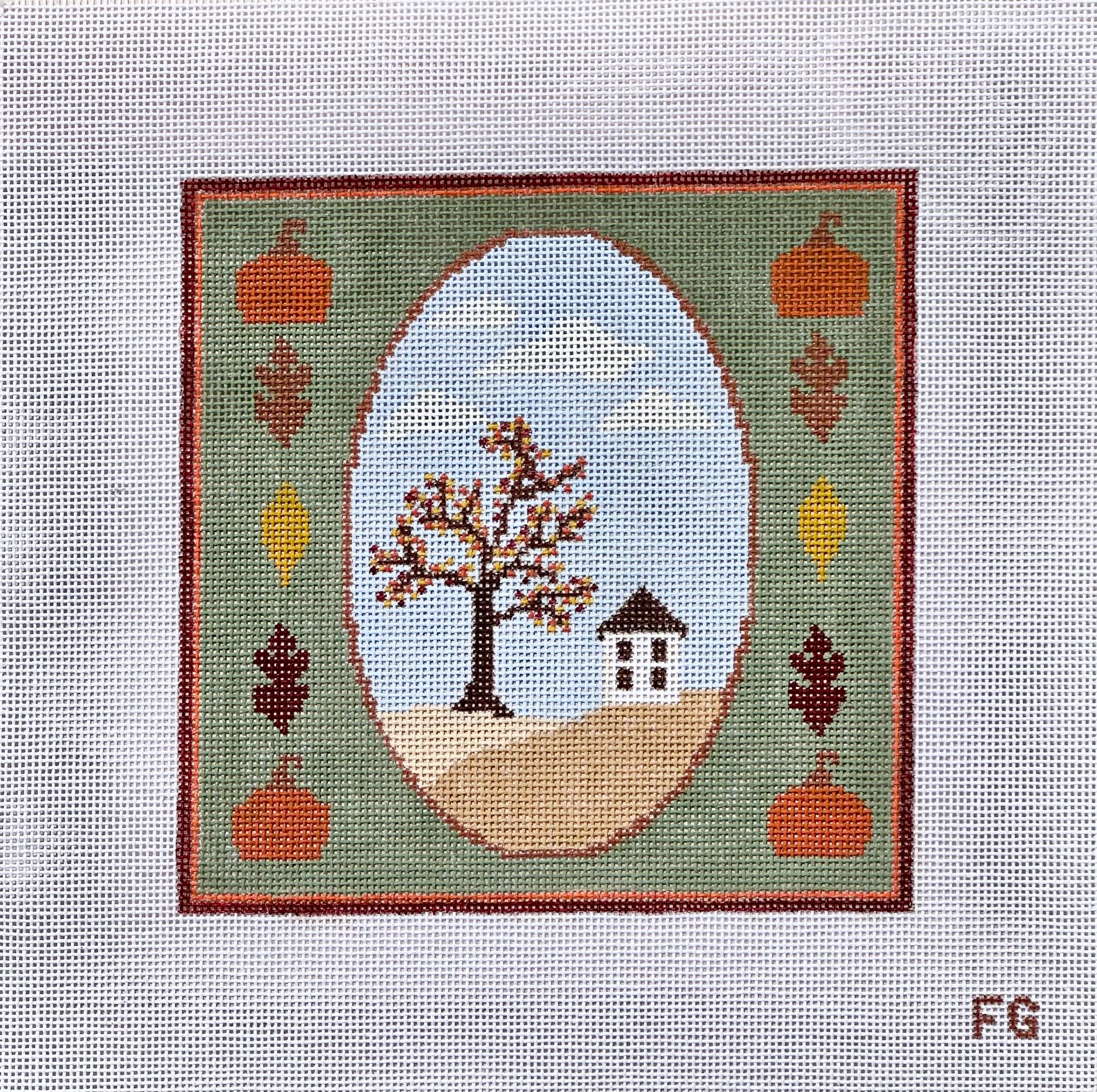 A square needlepoint canvas featuring a fall landscape design. The design has a green border with orange pumpkins, brown and yellow leaves, and a central oval showing a tree with brown and orange leaves, a small house, and a light blue sky.