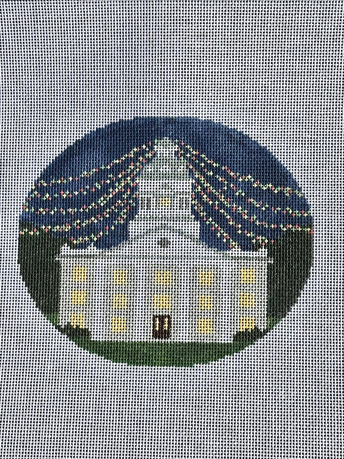 needlepoint canvas with white building and christmas lights 