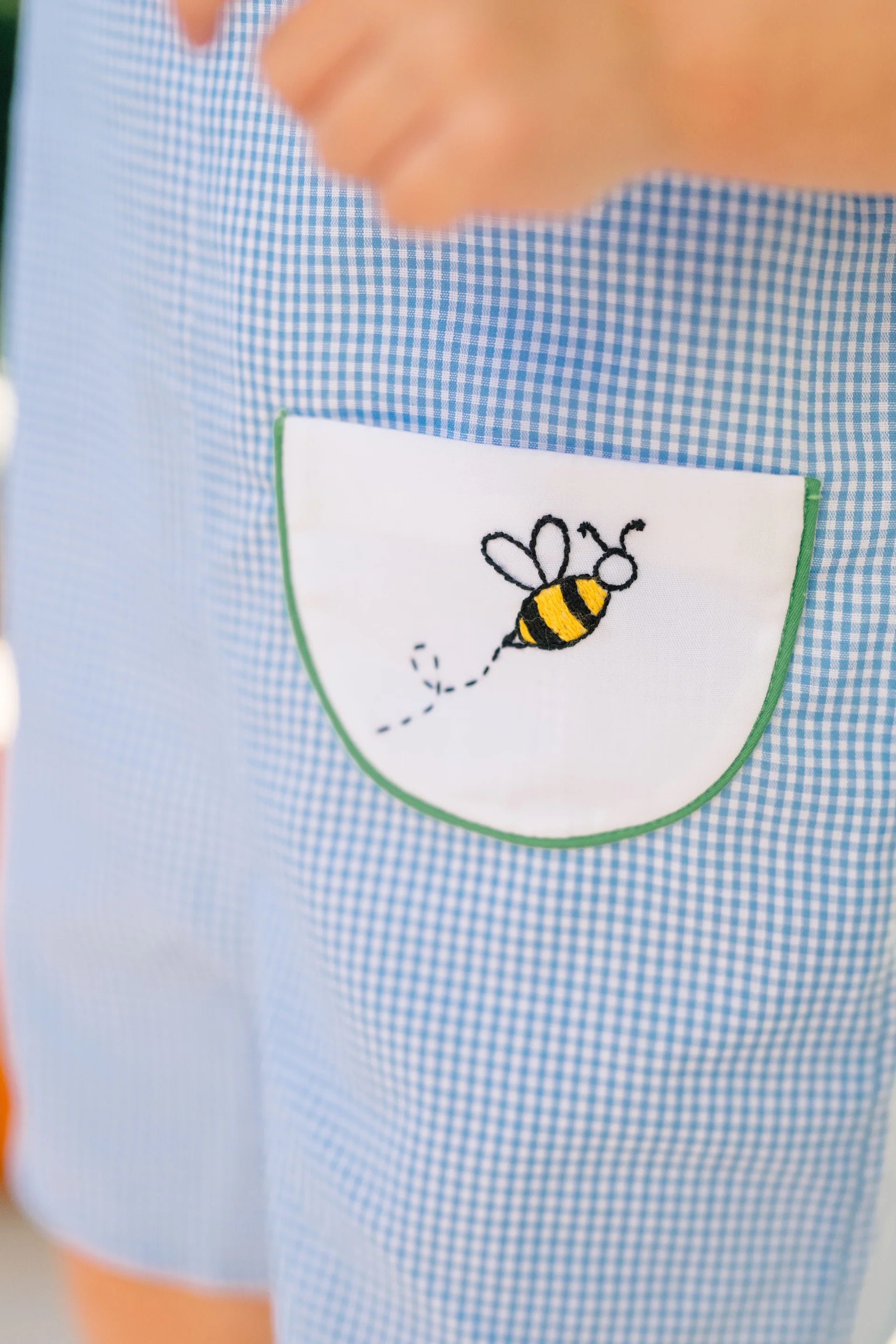 Blue checkered shirt with a embroidered bee design on the chest pocket.