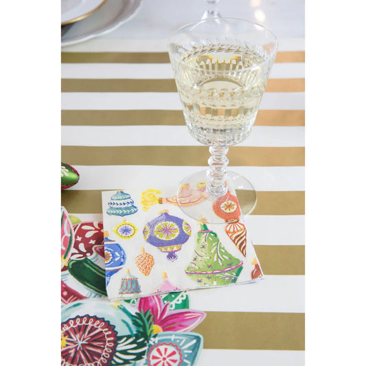 Colorful patterned coasters on a gold and white striped tablecloth with a glass of white wine.