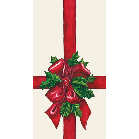 Decorative Christmas bow with red ribbon and green holly leaves on a beige background