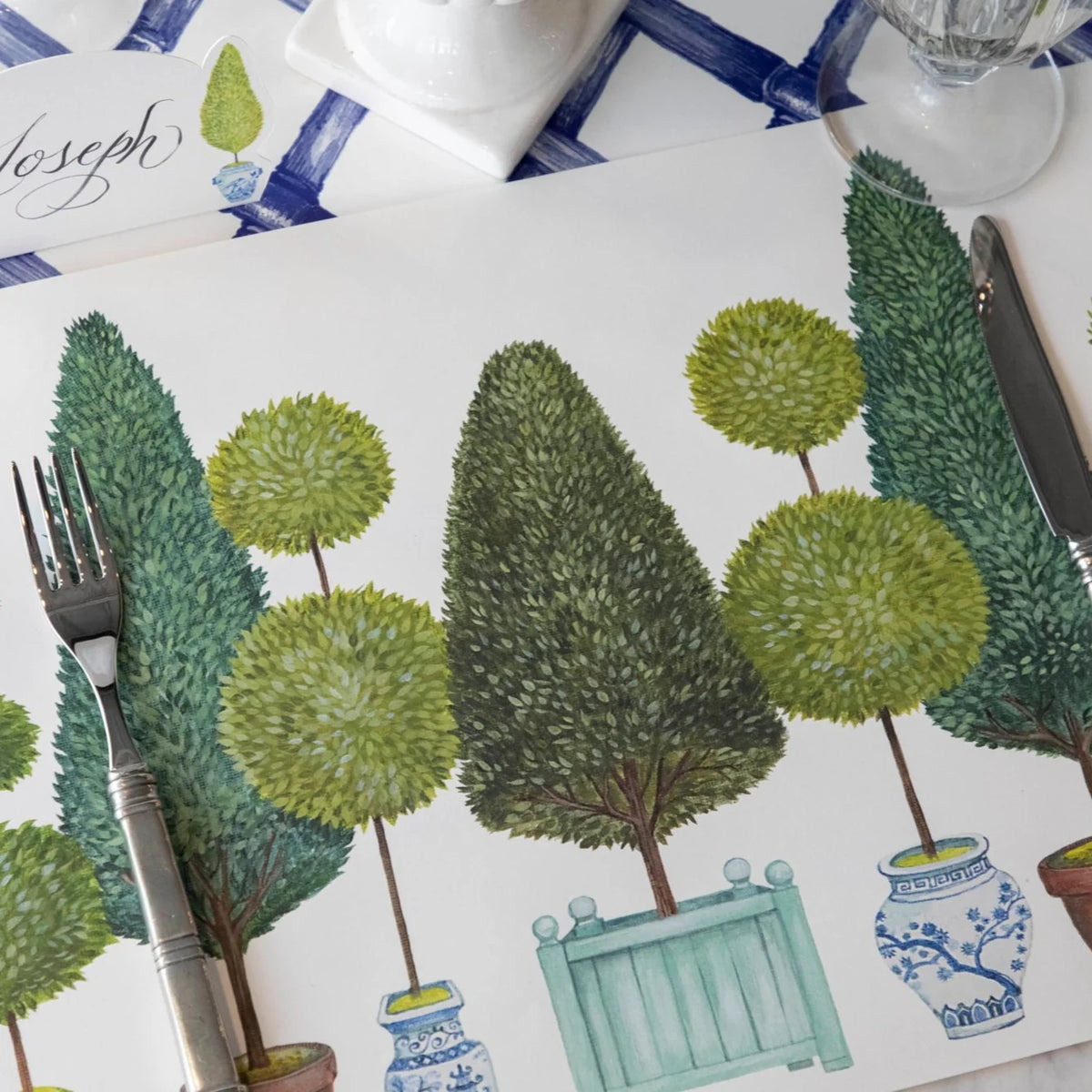 Placemat with green tree and plant design on a table setting.