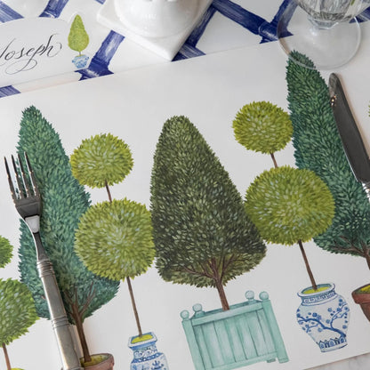 Placemat with green tree and plant design on a table setting.