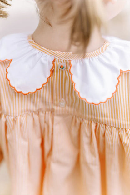 Close-up of a dress with a white collar and orange trim on a blurred background