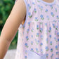 Child wearing a sleeveless dress with floral pattern and pocket, outdoors.