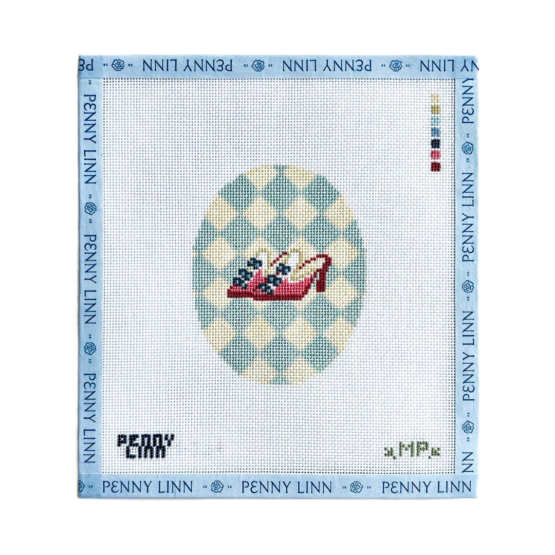 A Penny Linn needlepoint canvas featuring a red high-heeled shoe with blue and white flowers on a light blue and cream checkered oval background, surrounded by a blue border printed with the brand name.