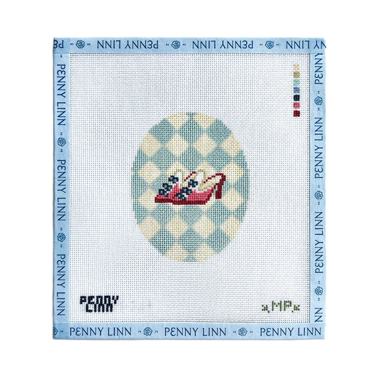 A Penny Linn needlepoint canvas featuring a red high-heeled shoe with blue and white flowers on a light blue and cream checkered oval background, surrounded by a blue border printed with the brand name.