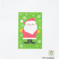 Cross-stitched pattern of Santa Claus on a green background with white snowflakes.