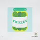 Cross-stitched design of a jar labeled 'Pickles' on a light blue background
