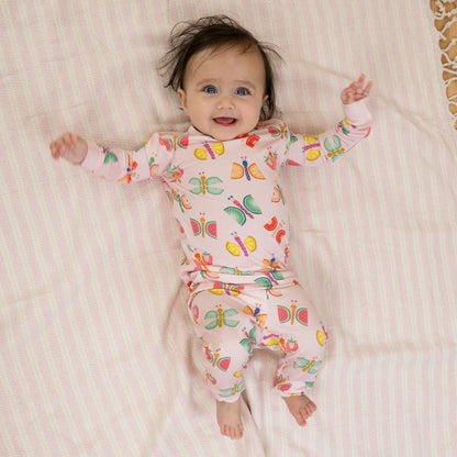 Baby wearing a colorful butterfly-patterned onesie on a striped blanket
