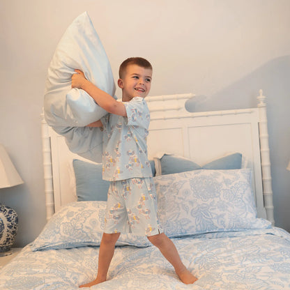 Child in pajamas playing with pillows on a bed in a bedroom