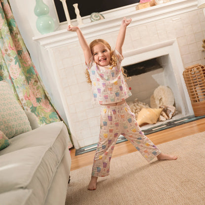 Child in pajamas jumping in a living room with a fireplace.
