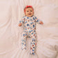 Baby wearing a colorful onesie with vehicle patterns on a soft pink blanket