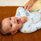 Baby lying down wearing a light blue onesie with colorful patterns.