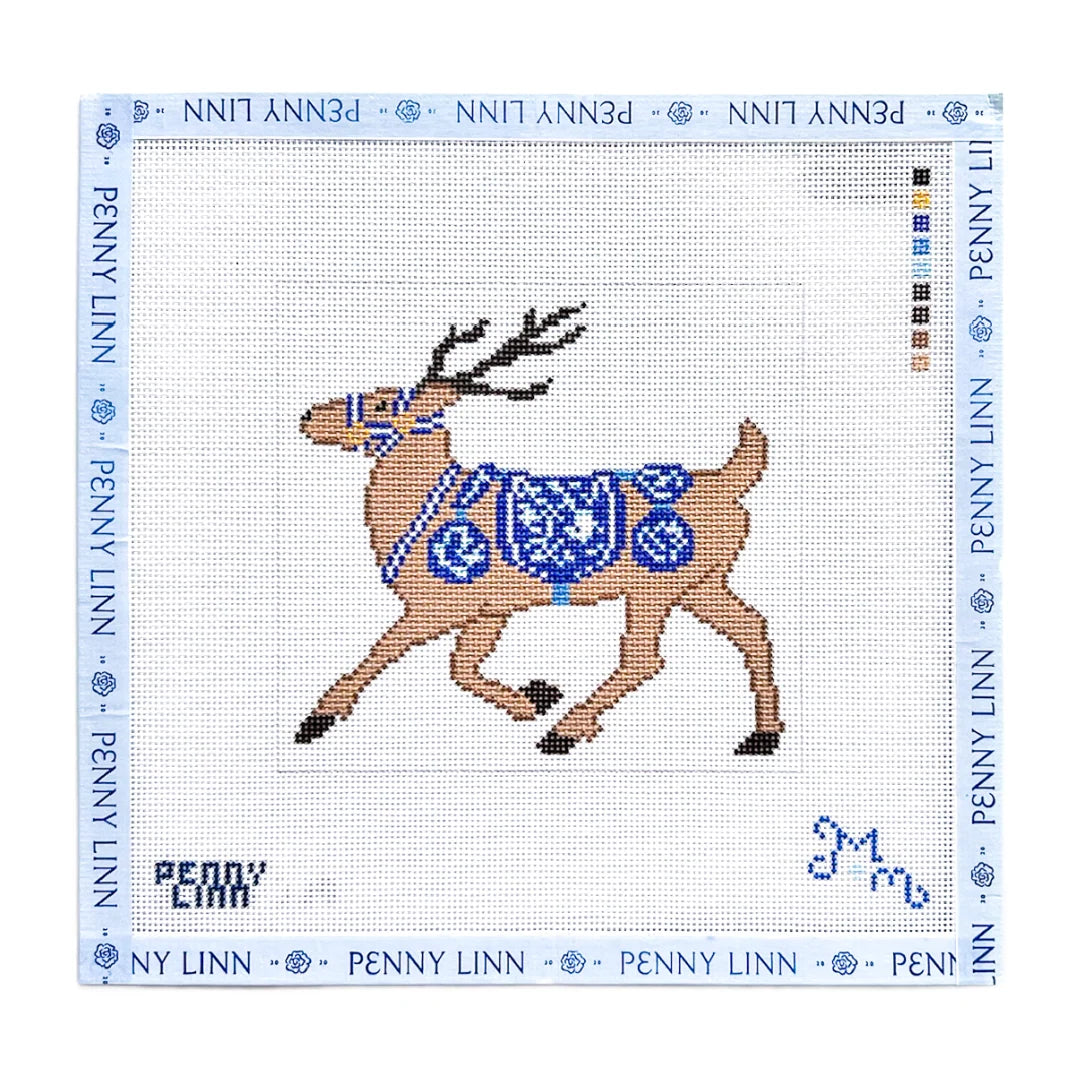 A Penny Linn needlepoint canvas featuring a brown reindeer with a blue patterned saddle and bridle, on a white grid background with a blue border printed with the brand name.