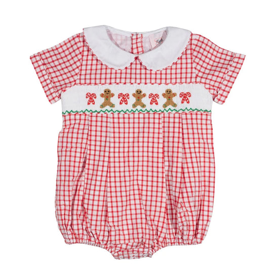 A baby romper in a red and white gingham pattern, featuring a white Peter Pan collar, a smocked chest band with embroidered gingerbread men and candy canes, and a green zigzag border.