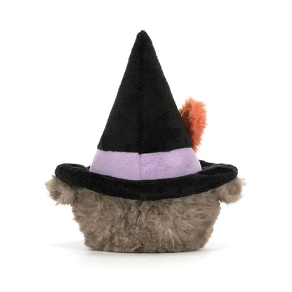 Plush toy resembling a cat in a witch hat with a purple band and orange feather on a white background