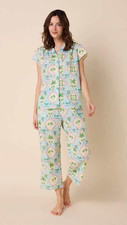 A woman wearing a capri pajama set with a geometric pattern that includes palm trees.