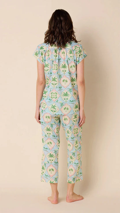A woman wearing a capri pajama set with a geometric pattern that includes palm trees.