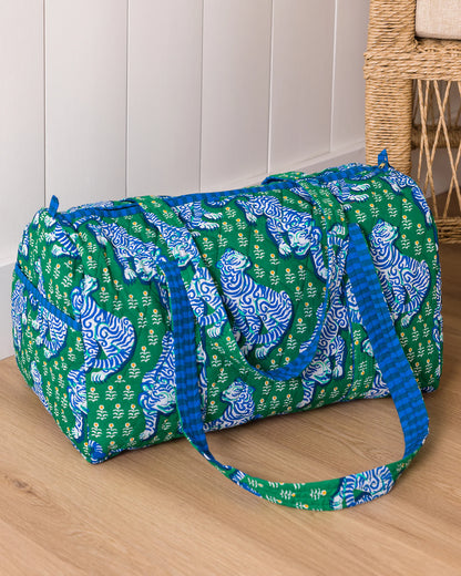 Green duffel bag with blue tiger pattern on a wooden floor