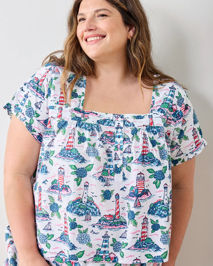 Woman wearing a blouse with lighthouse pattern against a plain background