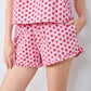 Pink pajama set with red heart pattern on a plain background