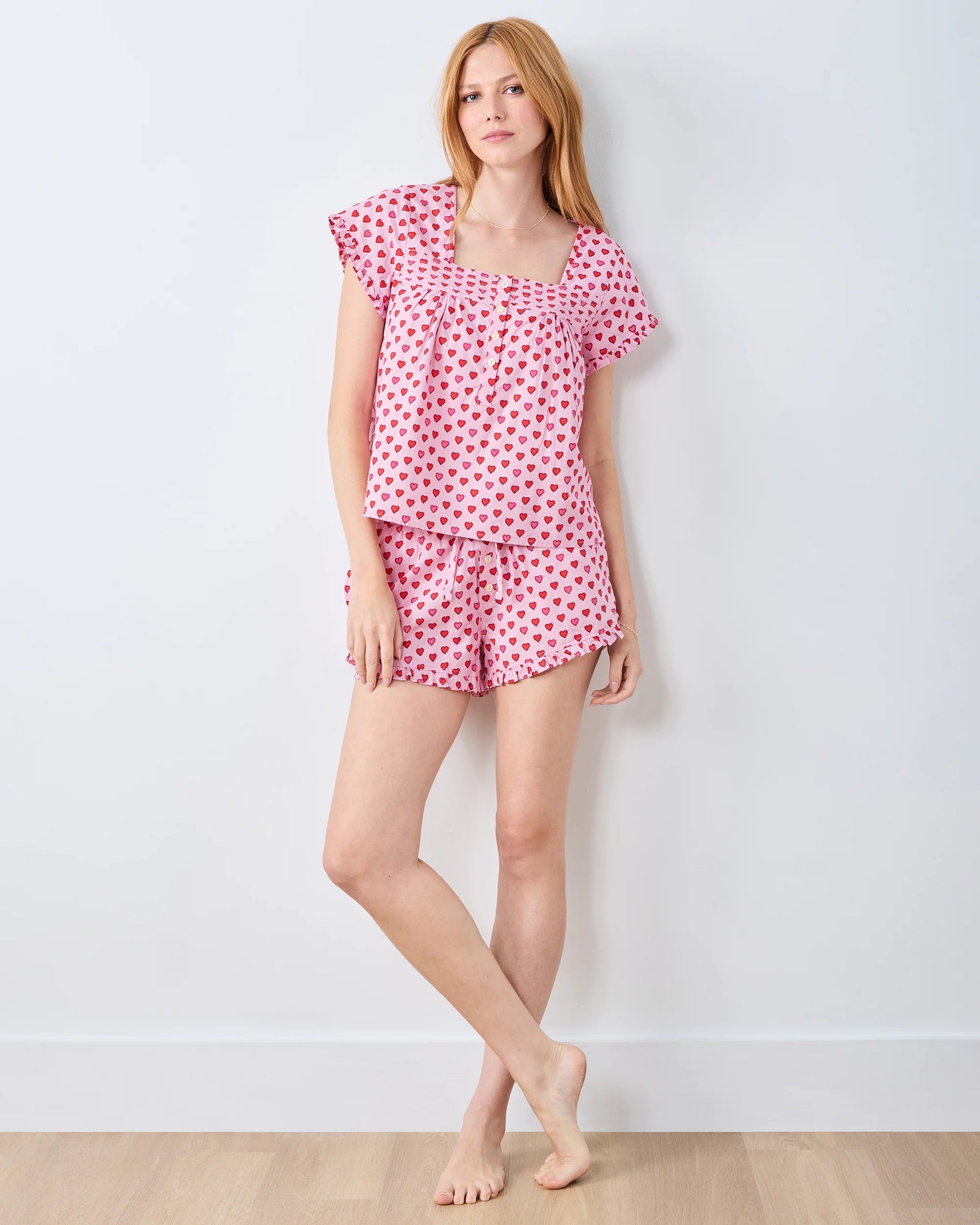 Woman wearing a pink heart pajama set against a white background