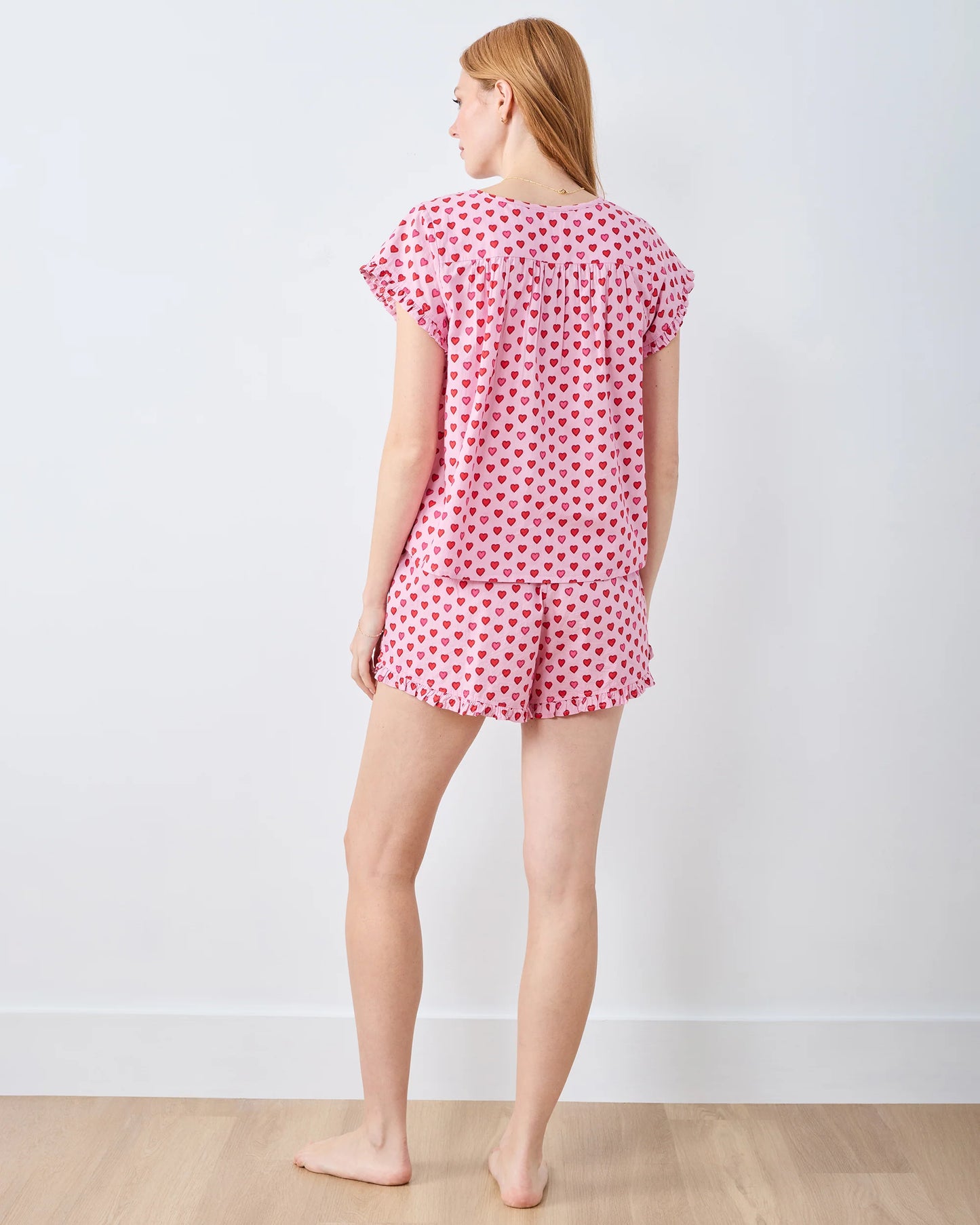 Woman wearing a pink heart pajama set against a white background