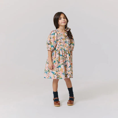 Young girl wearing a floral dress on a plain background